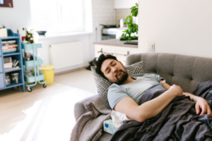 Man laying on a couch with stomach pain from stomach flu.