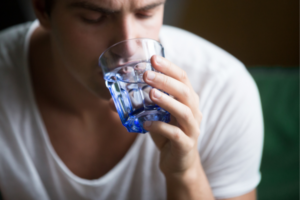 Man drinking water to stay hydrated after a hangover.