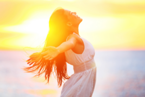 Happy woman outside in the sun, highlighting the role of vitamin D in reducing anxiety.