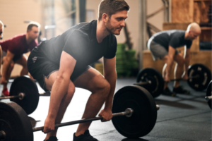 Man lifting weights in a gym, showing the B Complex benefits for men in muscle recovery and strength training.