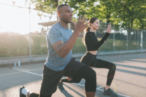 Two athletes stretching and cooling down outdoors after a workout session, staying hydrated post workout.