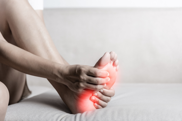 Close-up of a person holding their foot, showing nerve pain with a red highlight.