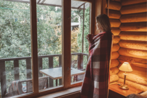 A woman wrapped in a blanket by a window, symbolizing winter wellness supported by IV therapy.