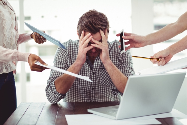 Stressed person with hands on head at a desk.